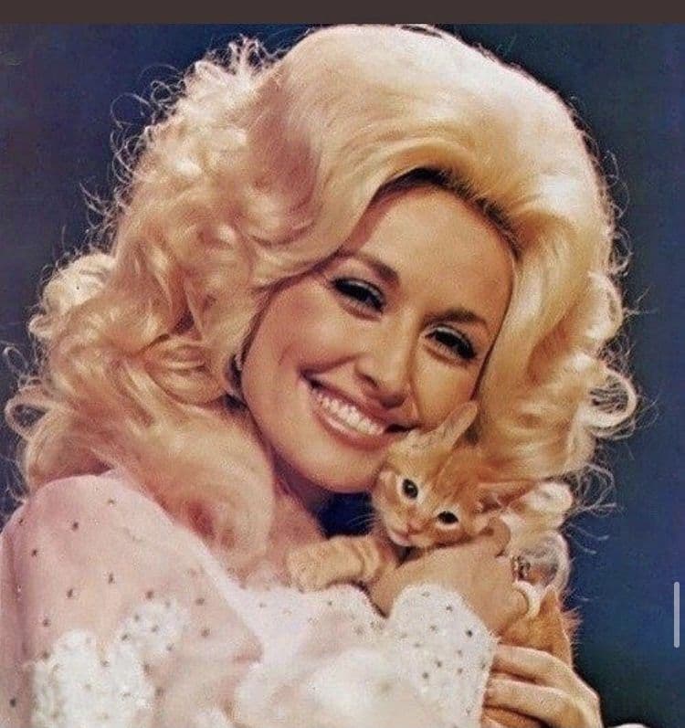 Dolly Parton in the 1970s, smiling, holding a ginger kitten